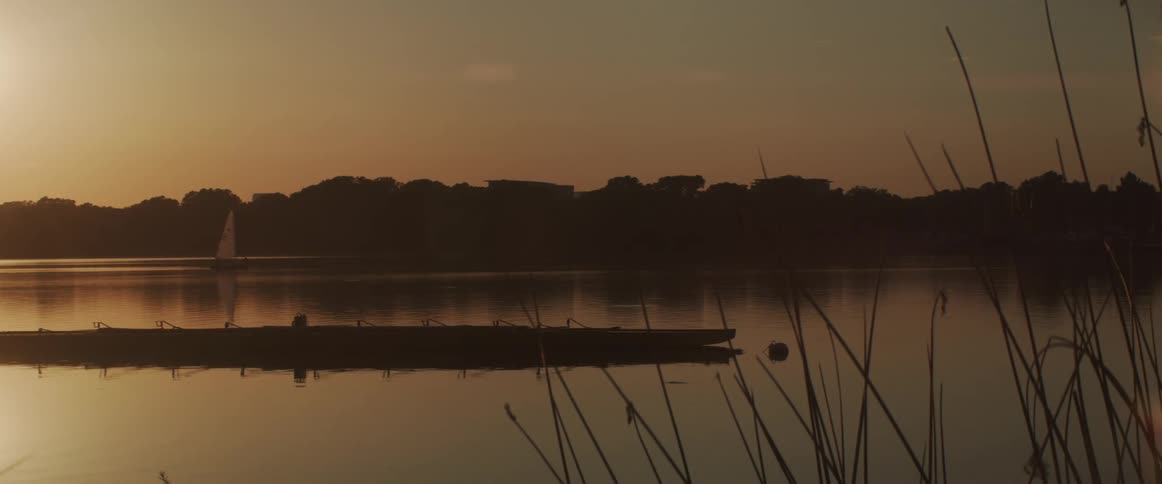 A sailboat slowly moves through a very still body of water