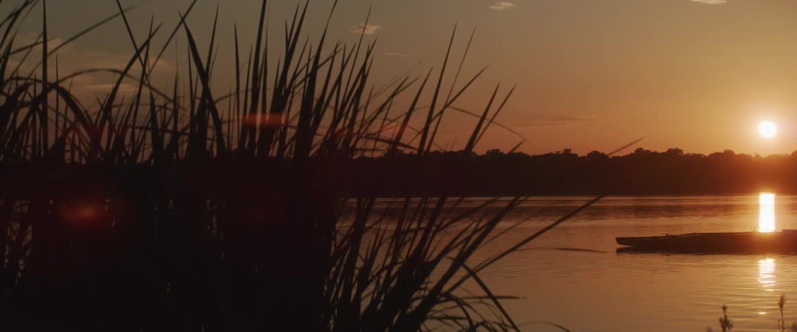 Rippling water near dock reflects sun coloring scene a warm reddish amber