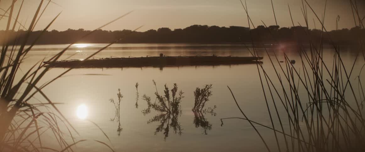 Wooden raft floating on the calm surface of a lake at sunset