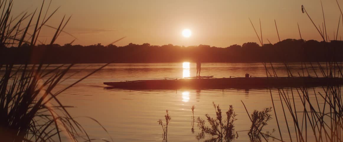 A person paddles by on a sup board on a very calm lake