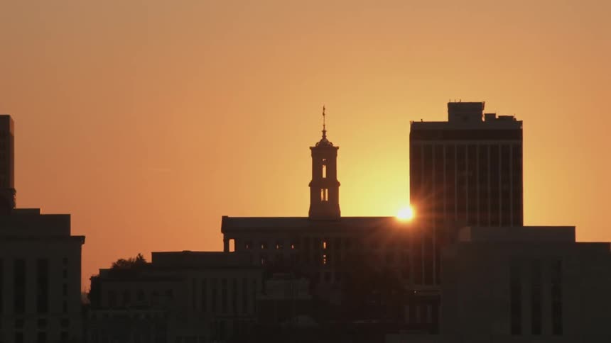 The sun slowly sets behind buildings