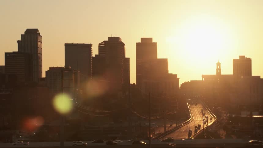 Cars are driving along roads in a city at sunset