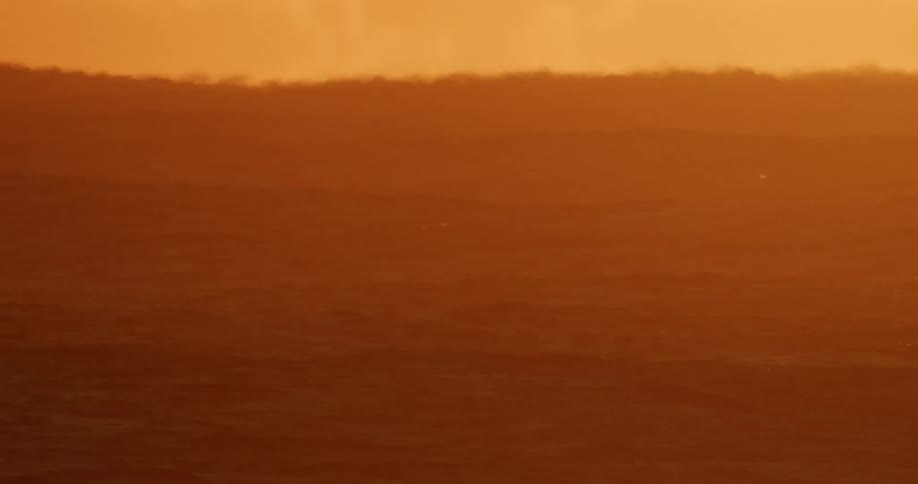 The ocean with waves reflecting sunlight with the sky and clouds in the background