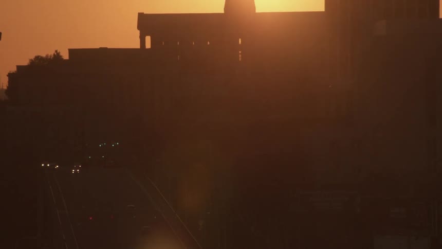 The sun is setting behind a building in a dark area