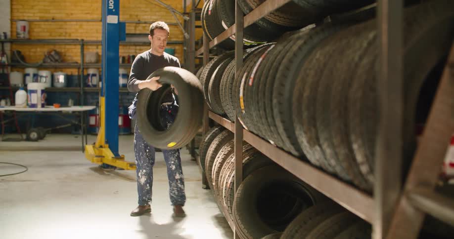 A man grabbing a tire off of a shelf in a shop