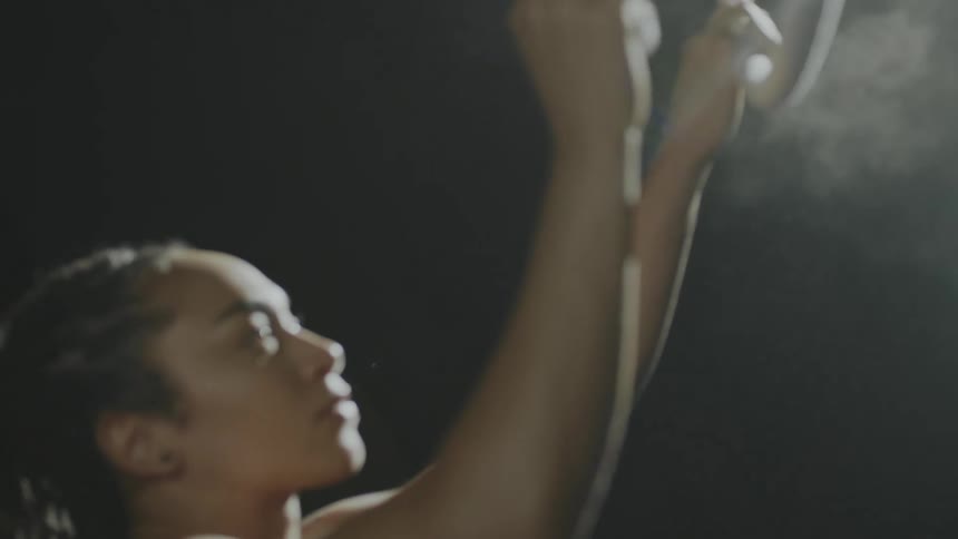 A female performer applying chalk to a suspended hoop