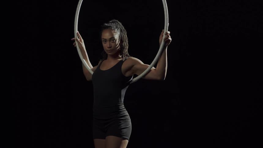 Strong fit muscular woman hanging from a ring looks at the camera