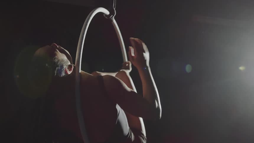 A teenage girl spins in a suspended ring as she performs acrobats