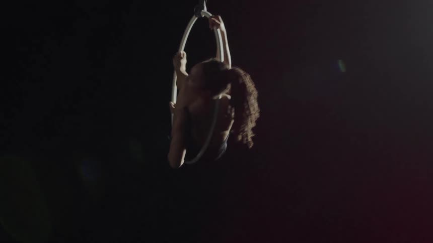 Young strong fit woman spinning on a ring hanging from the ceiling