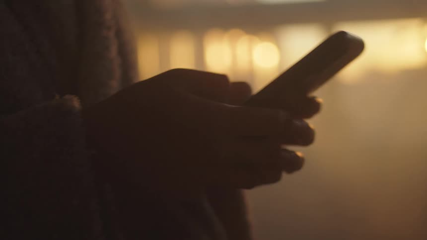 A female is quickly typing a message into her smart phone