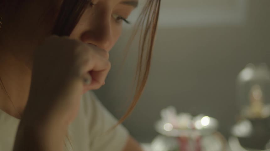 A young woman chews on a pen while thinking about what to write in her notebook
