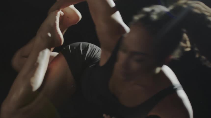 Young strong fit muscular woman spinning acrobatically on a ring hanging from the ceiling