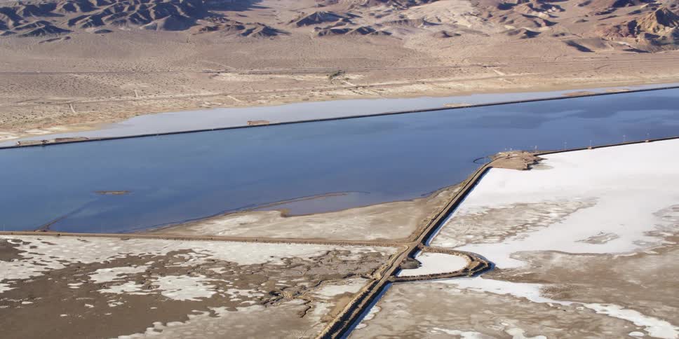 A layer of ice covers the top of an in ground pool in the middle of a dirt field