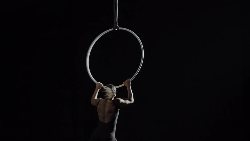 A female gymnast is performing on a large ring
