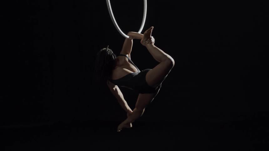 A woman is suspended from a ring by just her forearm as she spins around