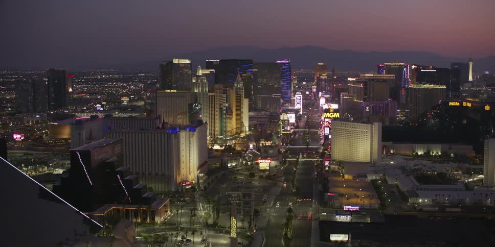 Pyramid building and other businesses line street in city center leading toward foggy mountains under red sky on the horizon
