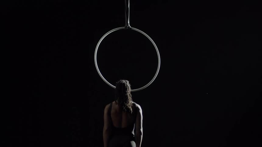 A female performance artist walking up to a suspended hoop