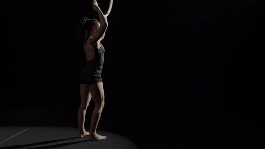 Young fit strong woman doing acrobatic stunts on a ring suspended from the ceiling