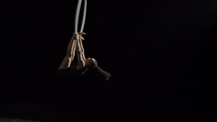 A woman is performing gymnastics on a hanging ring