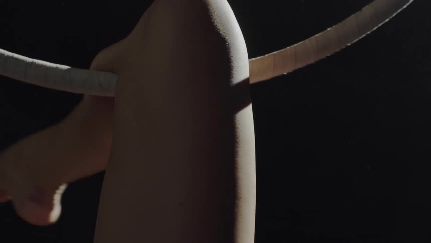 A person in a room hanging from a gymnast ring with their leg