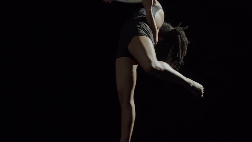 Young fit strong woman doing acrobatic stunts on a ring suspended from the ceiling