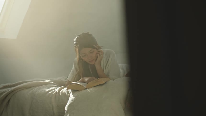A woman reading a book on a bed