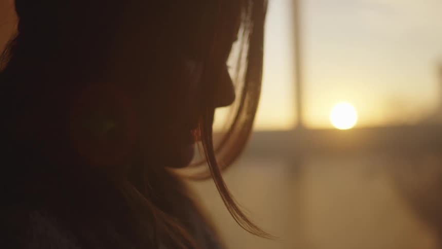 Silhouette of the profile of a woman standing near a window at sunset