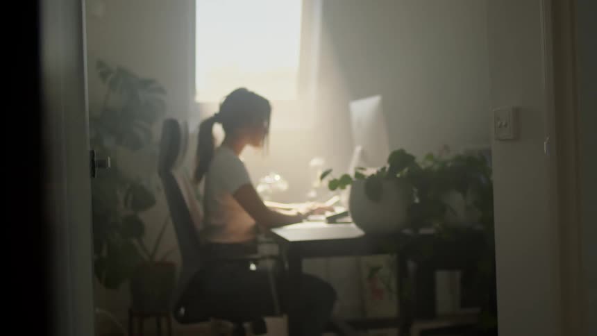 A woman sitting in a sunlit room with a computer