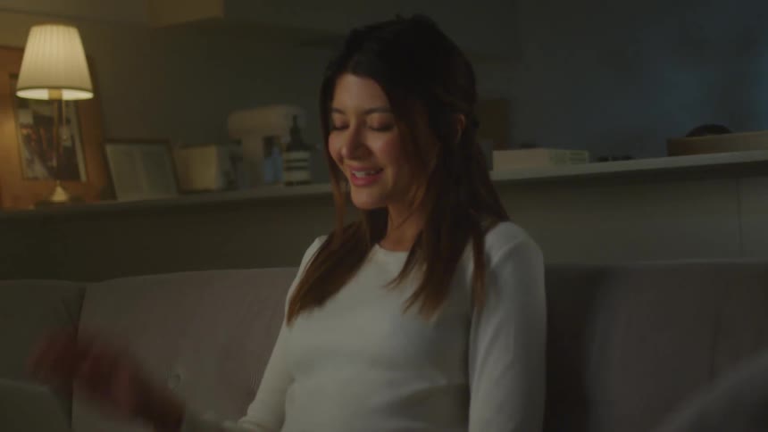 A woman smiling and waving while engaging in a video call on a laptop