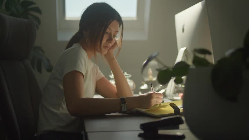 Young woman takes notes on a noebook over the desk at the office