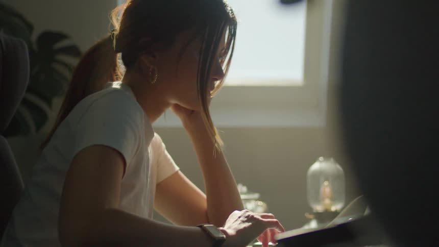 A woman working at a desk with a computer with her head resting on one hand