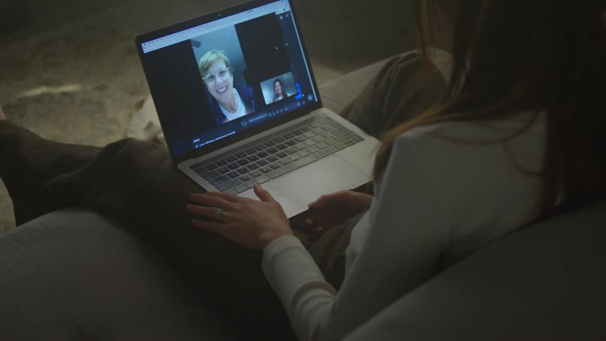 A woman in a room sitting on a couch using a laptop