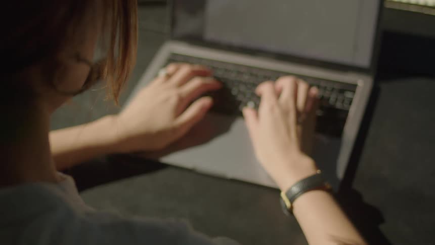 A woman typing on a laptop while sitting at a desk