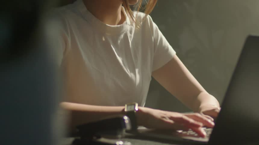 A woman is sitting down typing on her laptop