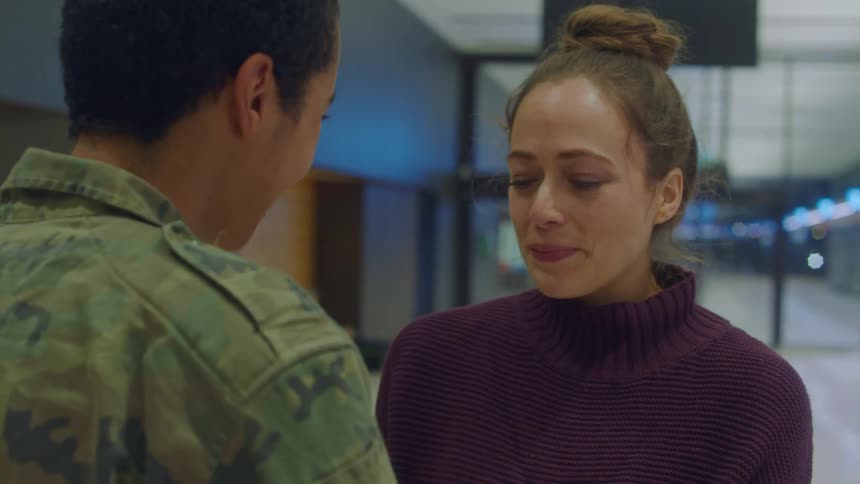 A woman crying while hugging a servicemember in an airport