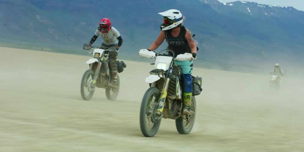 A group of people that are riding dirt bikes out in the desert