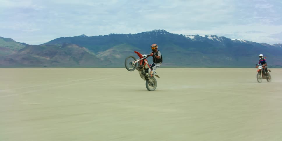 A group of people riding dirt bikes on a dry lake bed