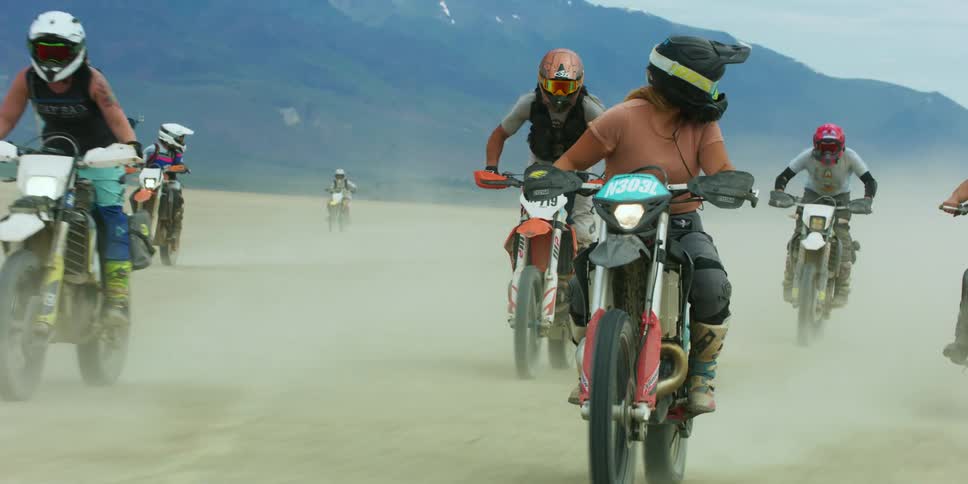 A group of people in helmets riding dirt bikes in a desert