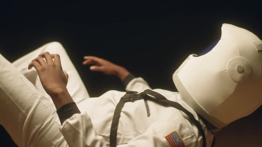 Man wearing an astronaut costume simulates floating in space