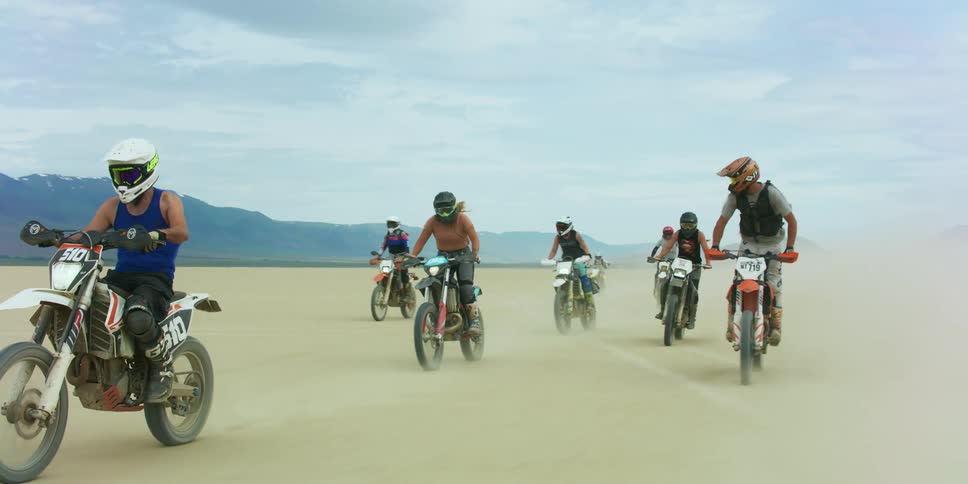 A group of friends ride dirt bikes in the desert