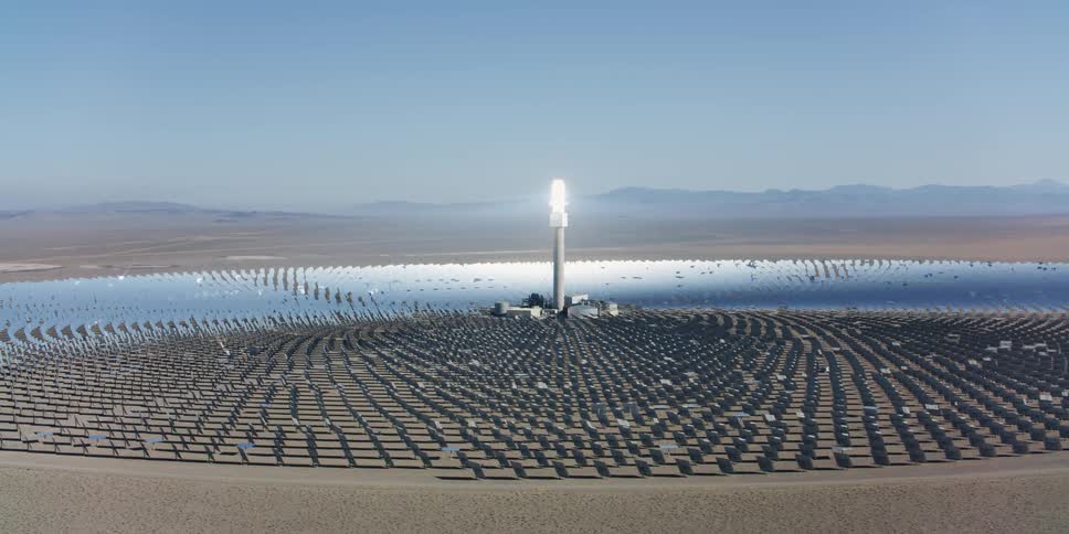 Aerial view of the bright spot atop a tower on a solar panel farm in the desert