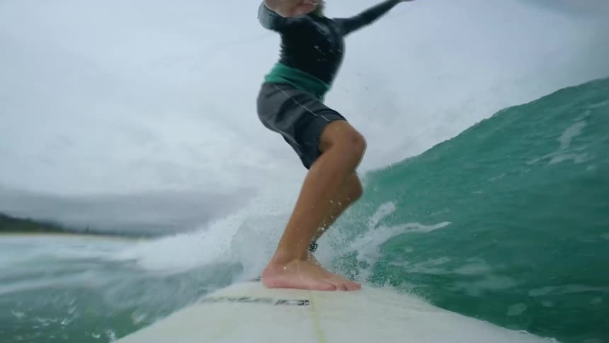 A male surfer riding an ocean wave on a cloudy day