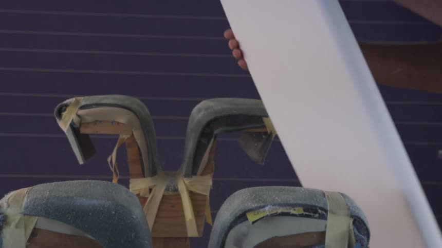 A man is sanding a new surfboard