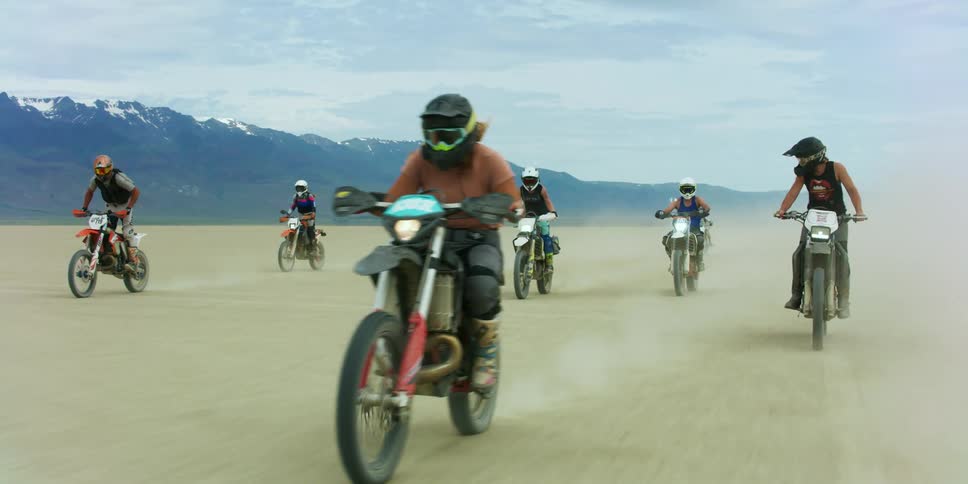 Group of people riding motorcycles on the desert near the mountain