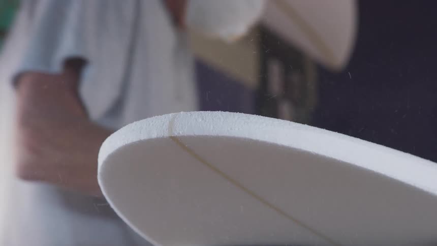 A man is polishing a surfboard