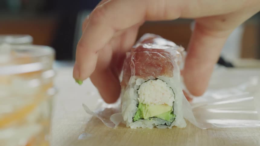 A chef is preparing sushi and cutting it with a knife