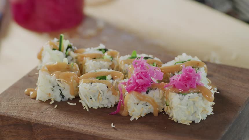 A chef is placing garnish on sushi