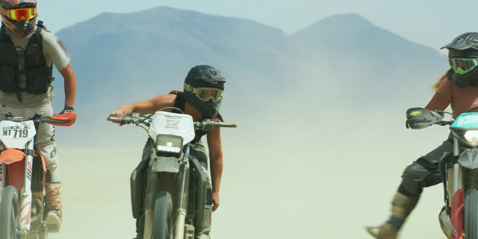 A group of people riding dirt bikes through the desert