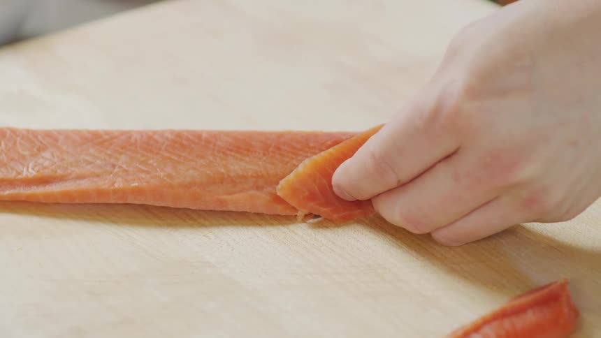 A cook is cutting slices of fish