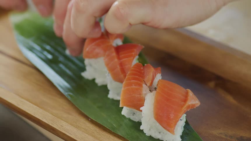A chef preparing sushi on a wood board in a restaurant